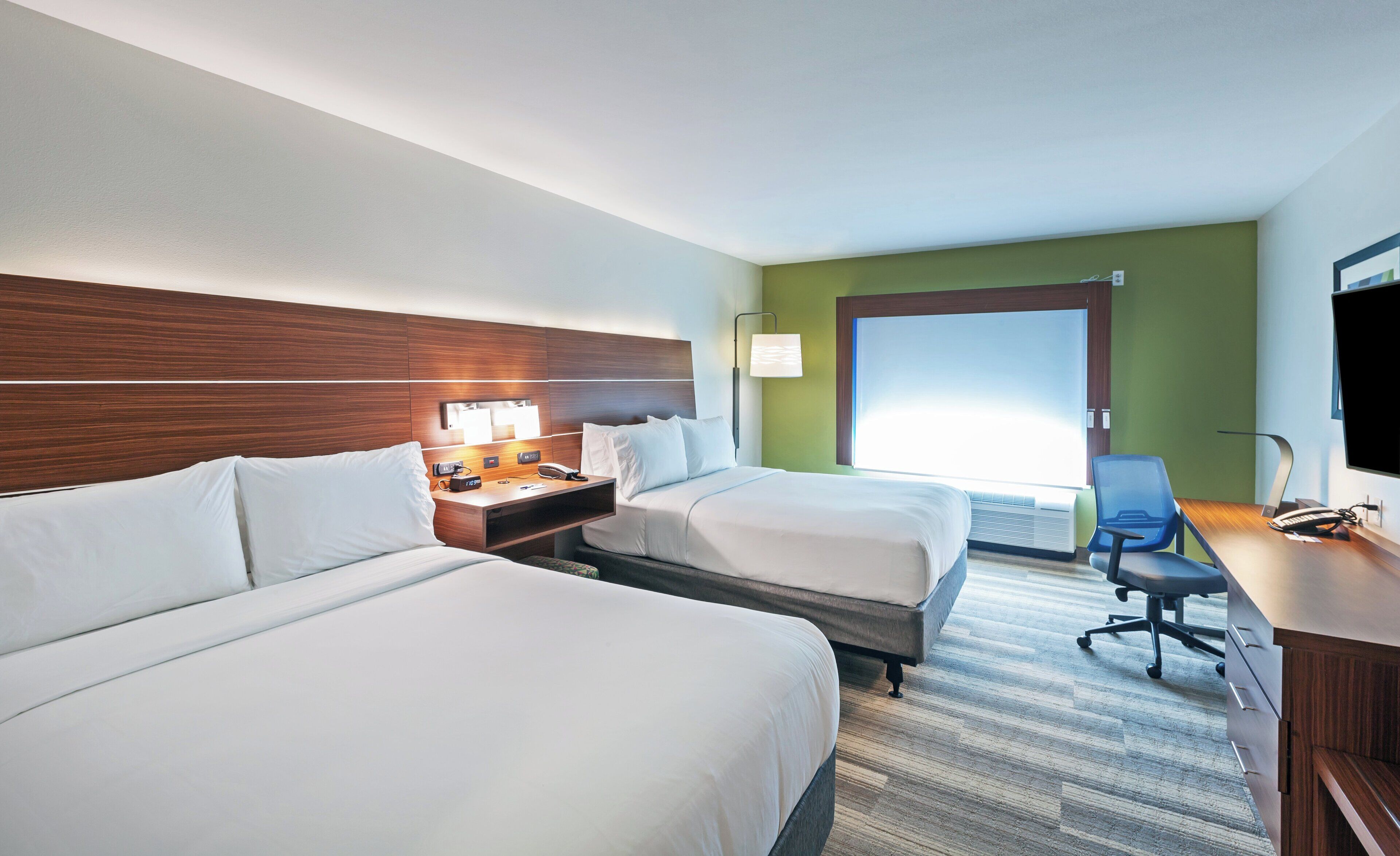 A hotel room with two beds, a desk with a computer, a telephone, and a television.