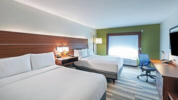 Ein Hotelzimmer mit zwei Betten, einem Schreibtisch, einem Computer, einem Telefon und einem Fernseher.