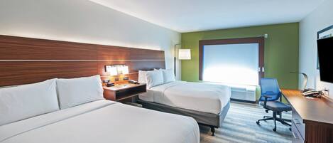 A hotel room with two beds, a desk with a computer, a telephone, and a television.