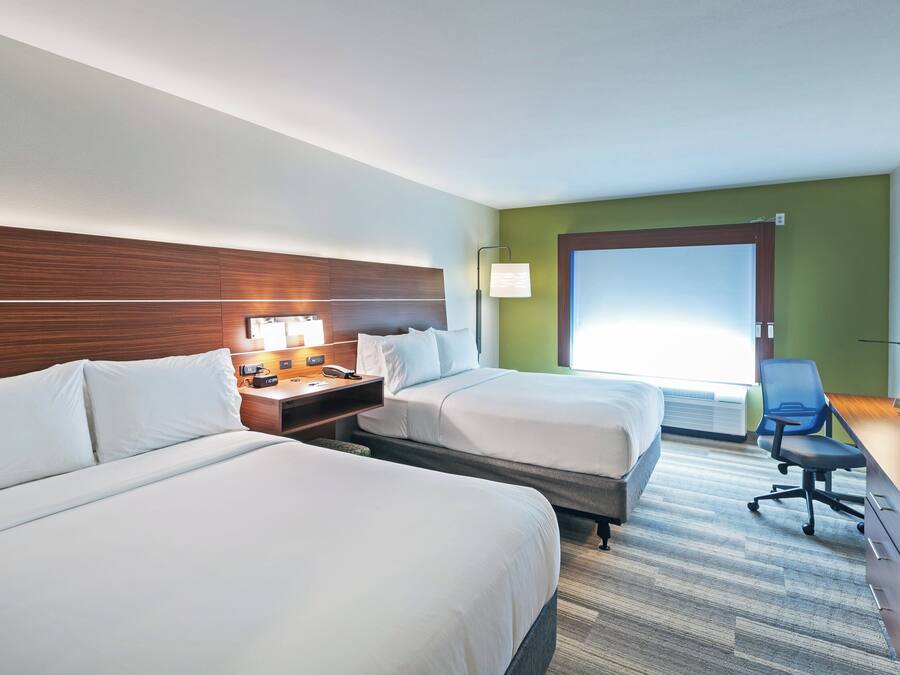 Ein Hotelzimmer mit zwei Betten, einem Schreibtisch, einem Computer, einem Telefon und einem Fernseher.