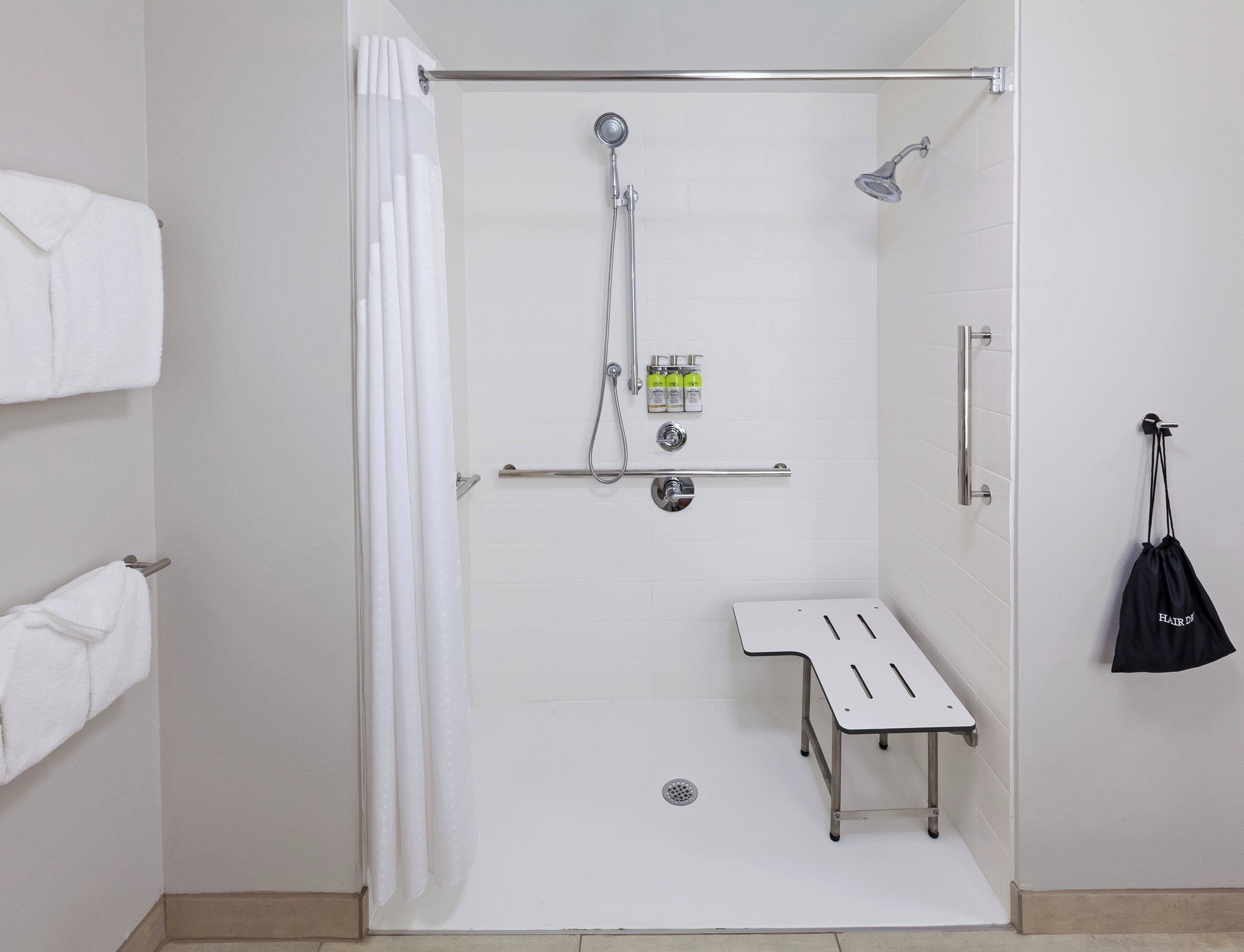 A shower area with a grab bar, a towel rack, and a small table.
