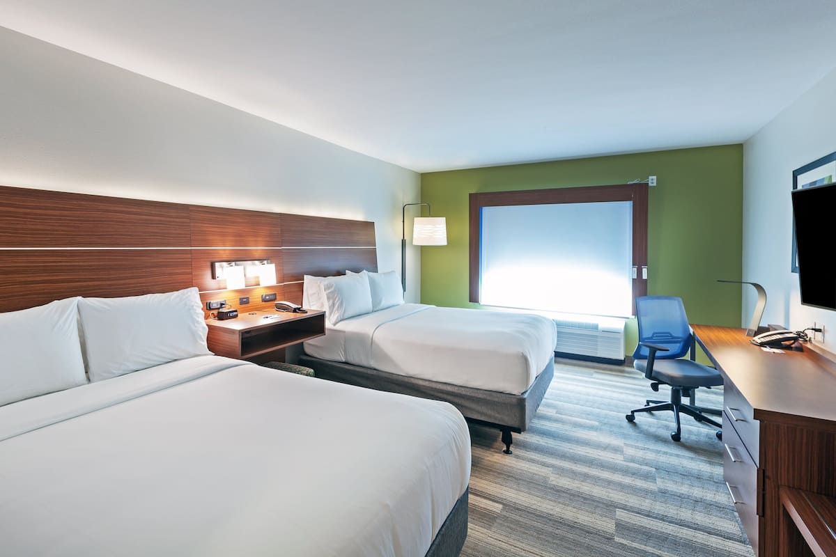 Une chambre d’hôtel avec deux lits, un bureau équipé d’un ordinateur, une lampe et un téléviseur.