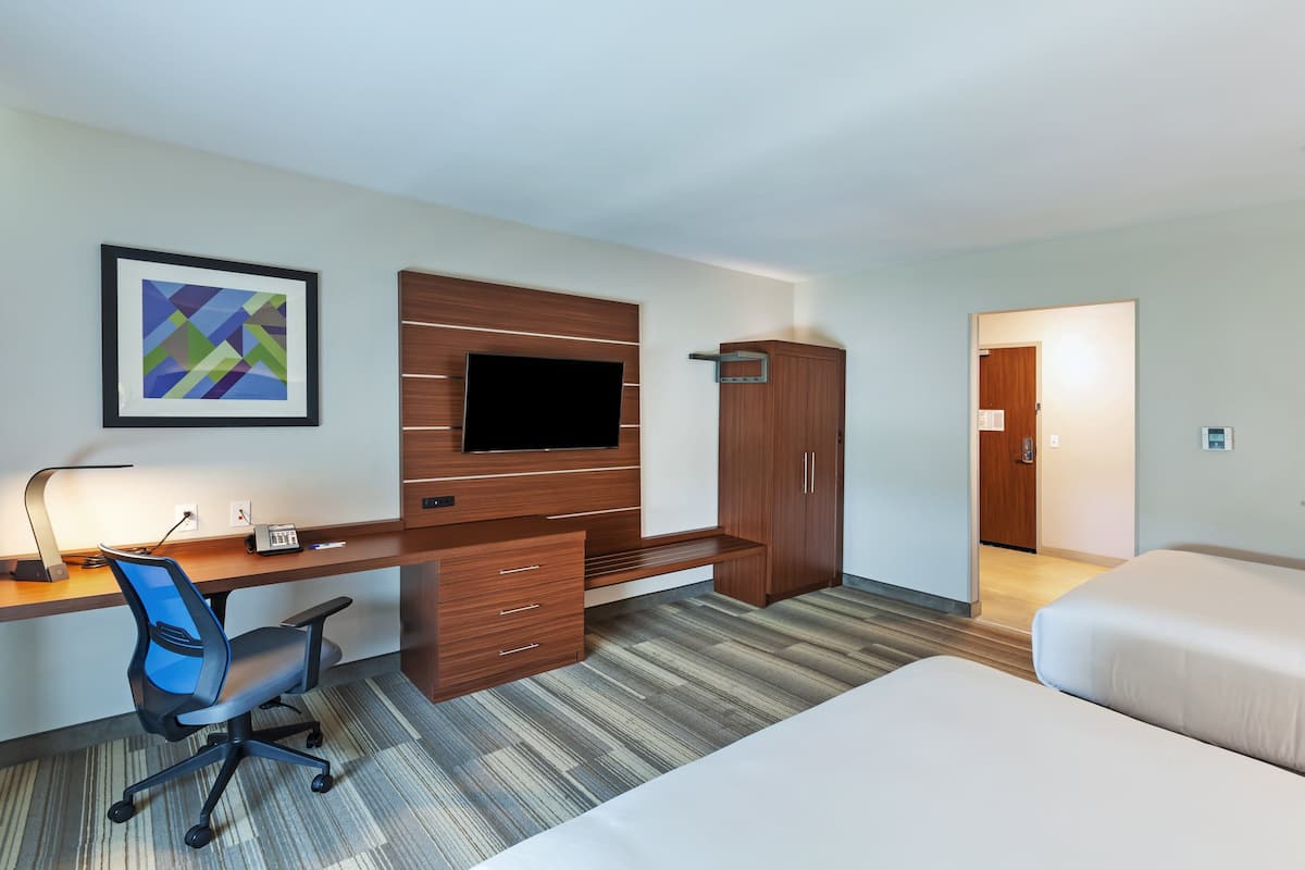 Une chambre d’hôtel équipée d’un bureau, d’une chaise, d’une télévision, d’une armoire et d’un lit.