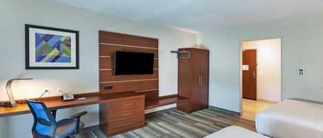 Une chambre d’hôtel équipée d’un bureau, d’une chaise, d’une télévision, d’une armoire et d’un lit.