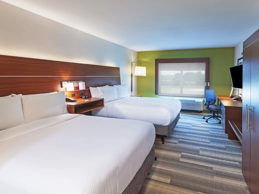 A hotel room with two beds, a desk with a chair, a television, and a large window.