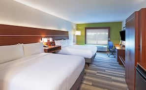 Une chambre d’hôtel avec deux lits, un bureau avec une chaise, une télévision et une grande fenêtre.