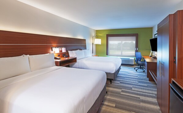 Ein Hotelzimmer mit zwei Betten, einem Schreibtisch mit Stuhl, einem Fernseher und einem großen Fenster.