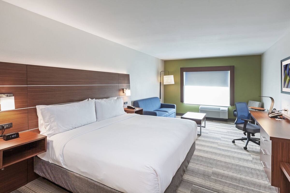 Une chambre d’hôtel avec un grand lit, un bureau, une chaise, une télévision et une fenêtre.