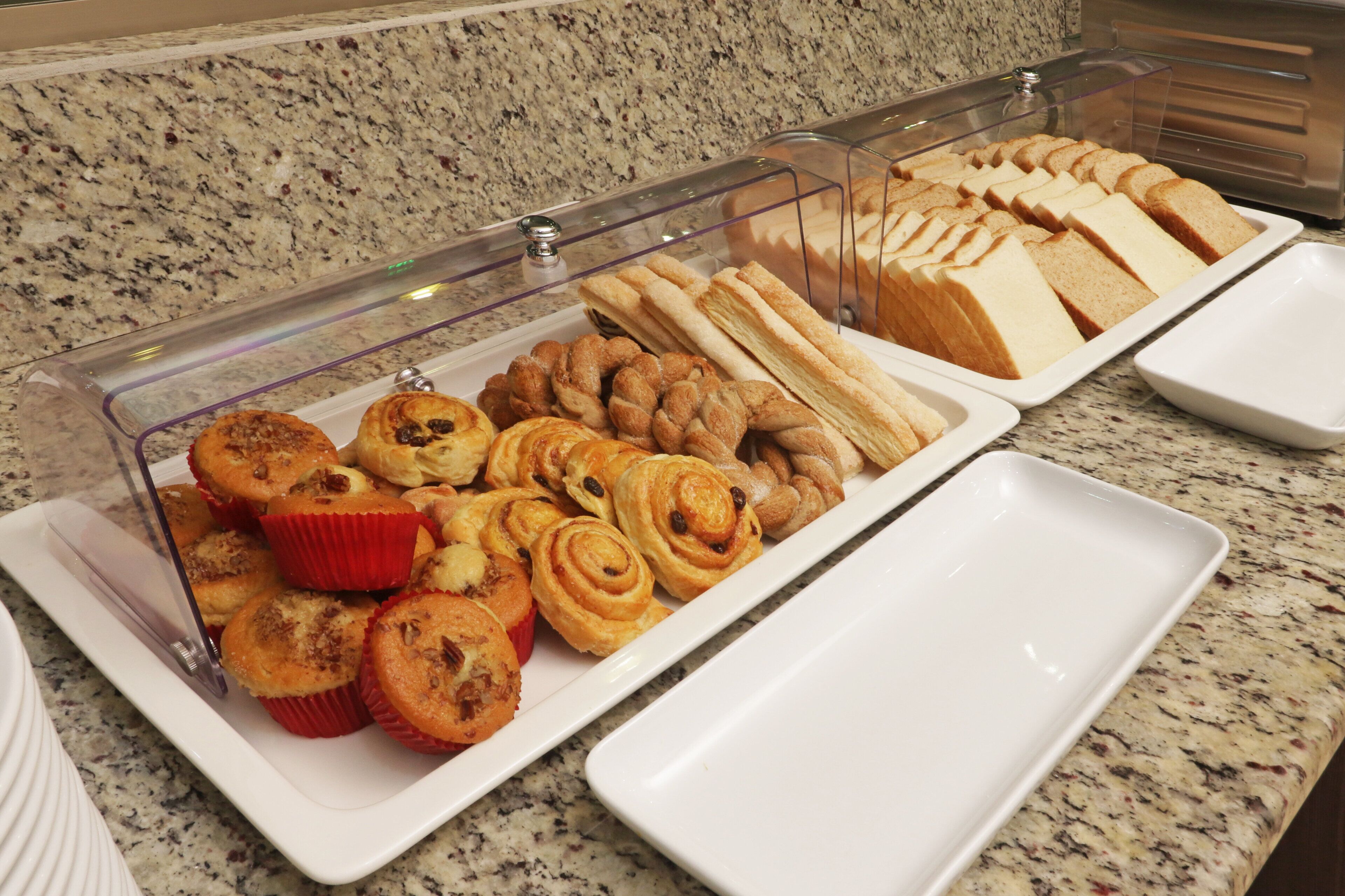 Un bufé con diversas opciones de panadería, incluyendo pasteles y pan.