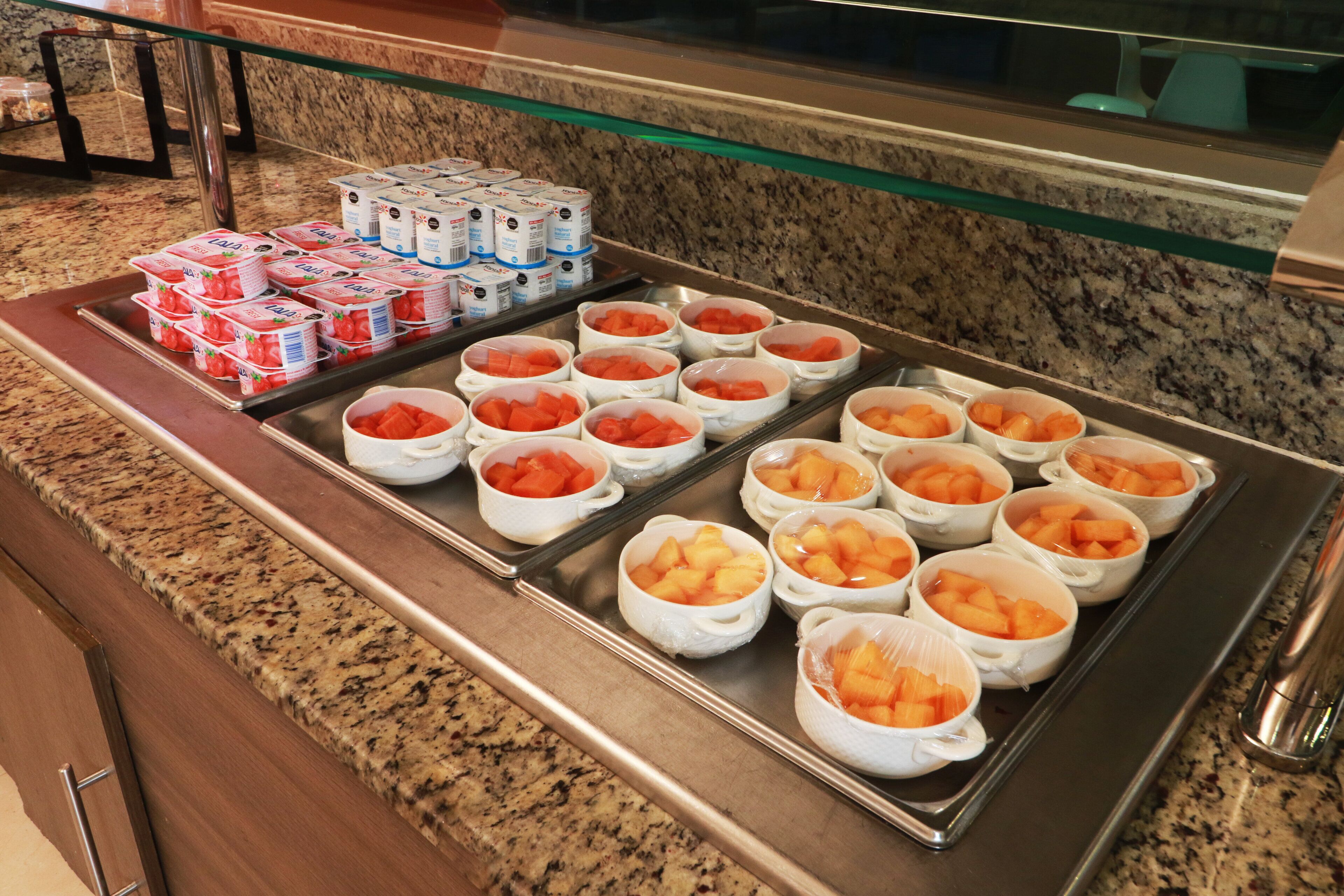 Ein Buffet mit verschiedenen Speisen, darunter Joghurt, Wassermelone und Ananas.