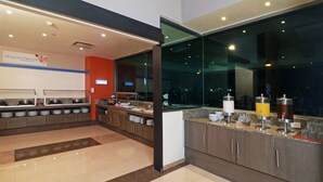 A modern kitchen with buffet-style food stations, a large window, and a clean, well-lit interior.