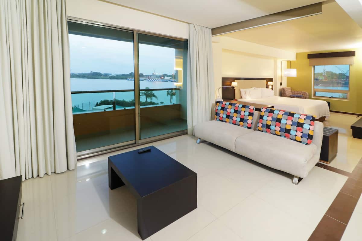 Quarto de hotel com varanda, um sofá, uma cama e uma mesa de centro.