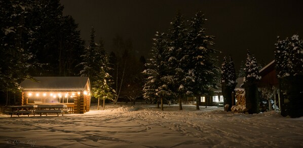 A snow-covered outdoor area with a wooden cabin and picnic tables.