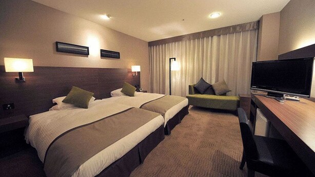 A hotel room with two beds, a desk, a television, and a window with curtains. - Hotel Tsu Center Palace (Tsu)