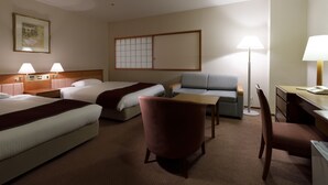 A hotel room with two beds, a desk, a chair, a sofa, and a lamp. - Hotel Tsu Center Palace (Tsu)