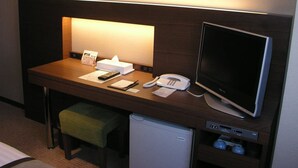 A hotel room desk with a computer, phone, and a small refrigerator. - Hotel Tsu Center Palace (Tsu)