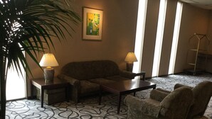 A hotel lobby with a sofa, armchairs, a coffee table, a lamp, a painting, and a patterned carpet. - Hotel Tsu Center Palace (Tsu)
