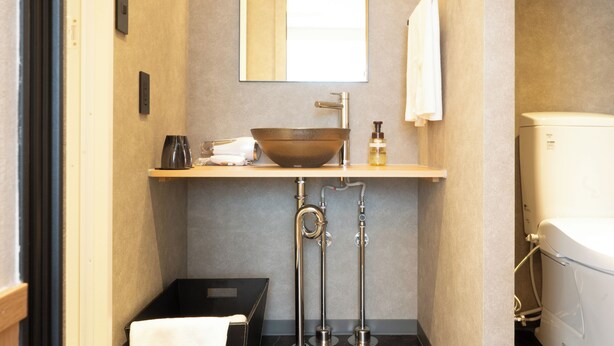 Une petite salle de bain comprenant un lavabo sur colonne, un miroir, un porte-serviettes et des toilettes.