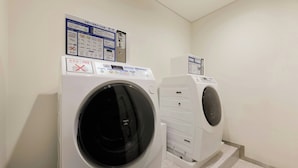 Uma área de lavanderia com duas máquinas de lavar de abertura frontal e um painel de controle com instruções.
