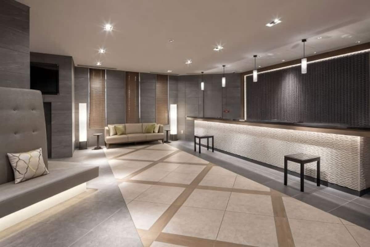 Eine moderne Hotelhalle mit einer Couch, einem Empfangstresen und einem gemusterten Boden.