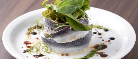 A dish with fish and greens on a white plate with sauce.