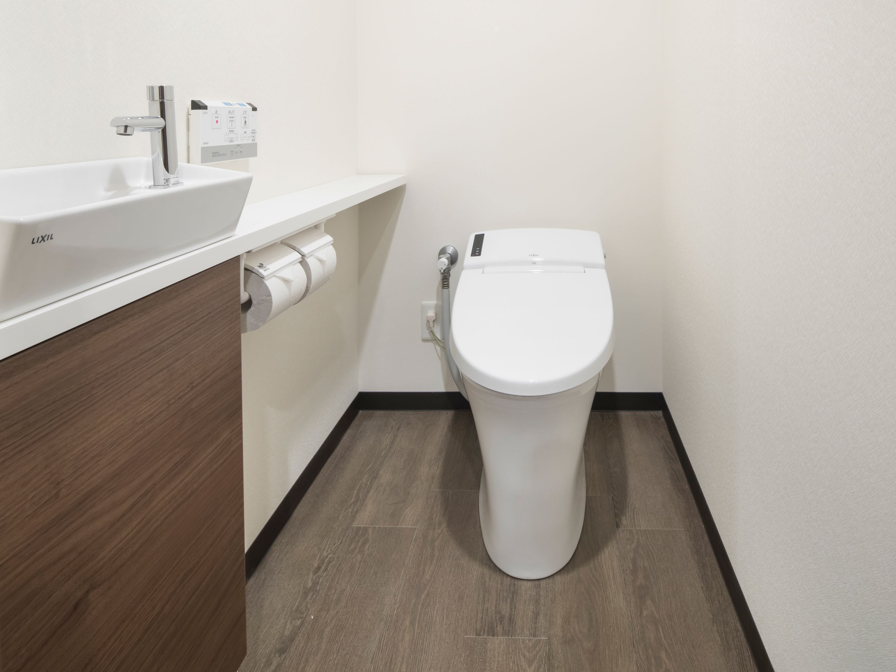 Une salle de bain moderne avec un lavabo blanc, des toilettes et un meuble-lavabo en bois.