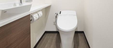 Une salle de bain moderne avec un lavabo blanc, des toilettes et un meuble-lavabo en bois.