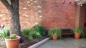 A brick wall with a bench and potted plants. - Albury Regent Motel (Albury)