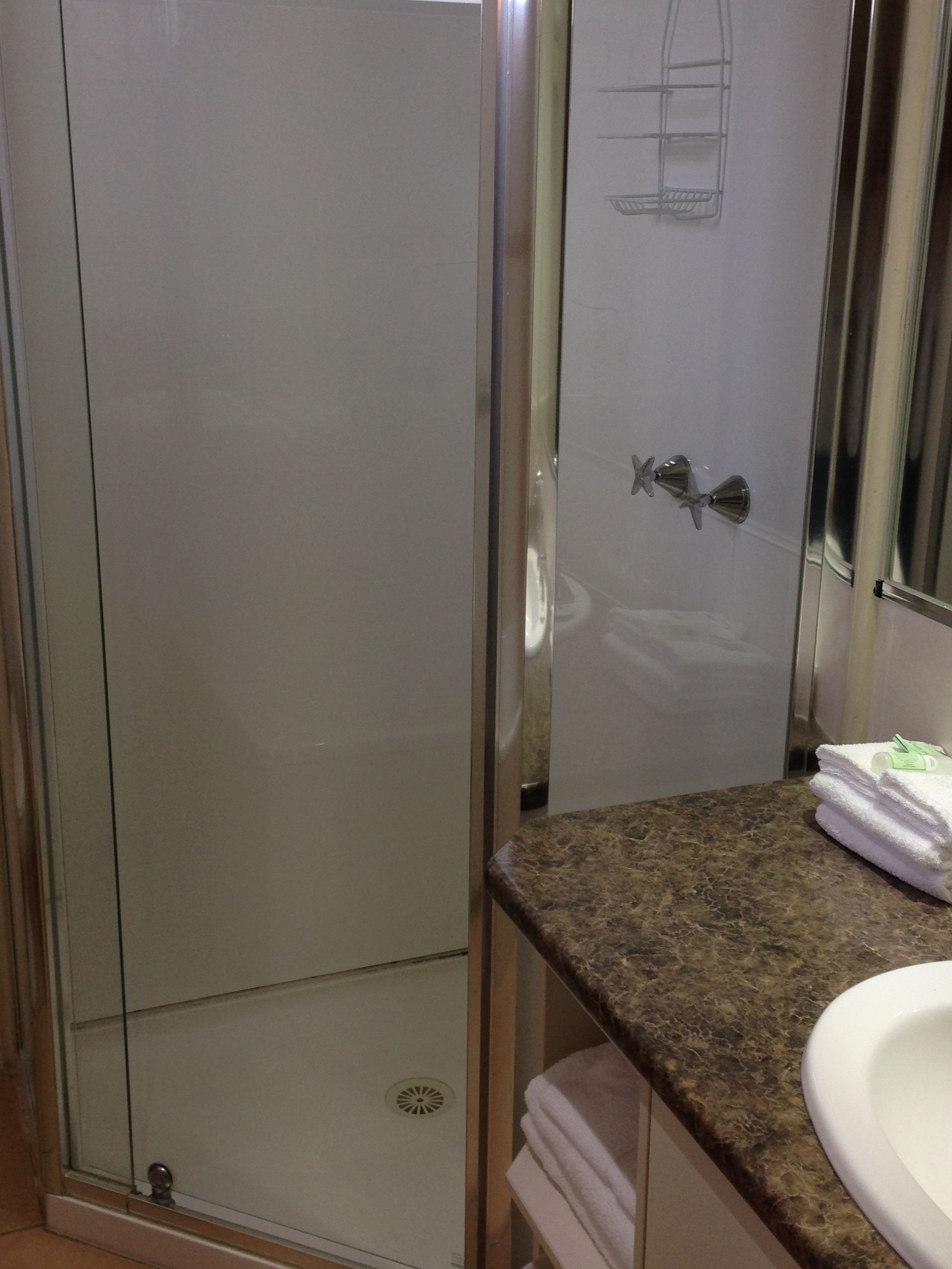Un baño con cabina de ducha de vidrio, un lavabo con encimera de mármol y un perchero para toallas.