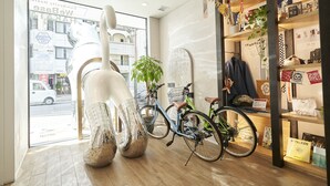 A modern interior with bicycles, a large sculpture, and a view of the street outside. - WeBase Hakata Hostel (Fukuoka)