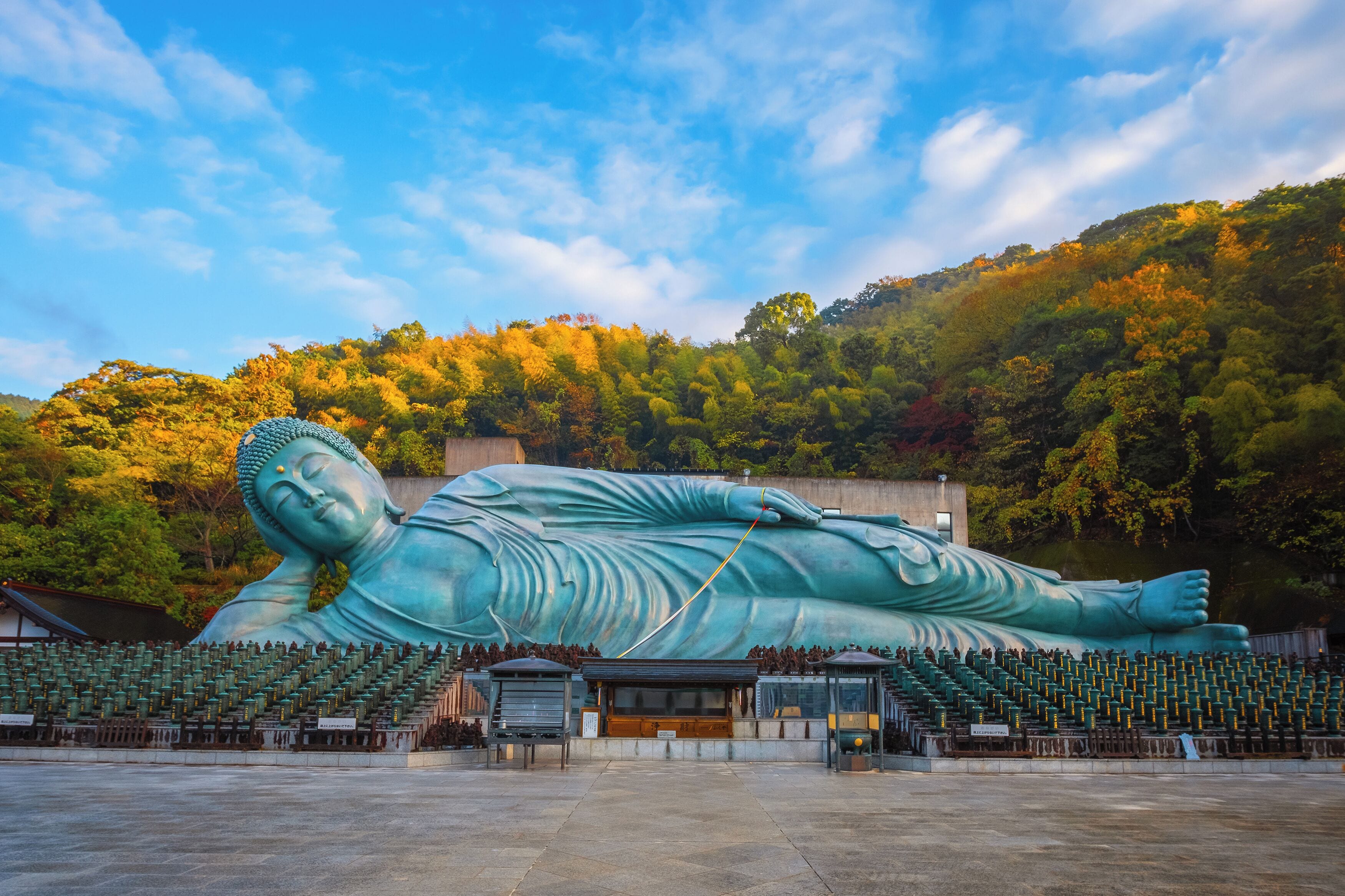 A large reclining Buddha statue in a spacious outdoor area with tiered seating.