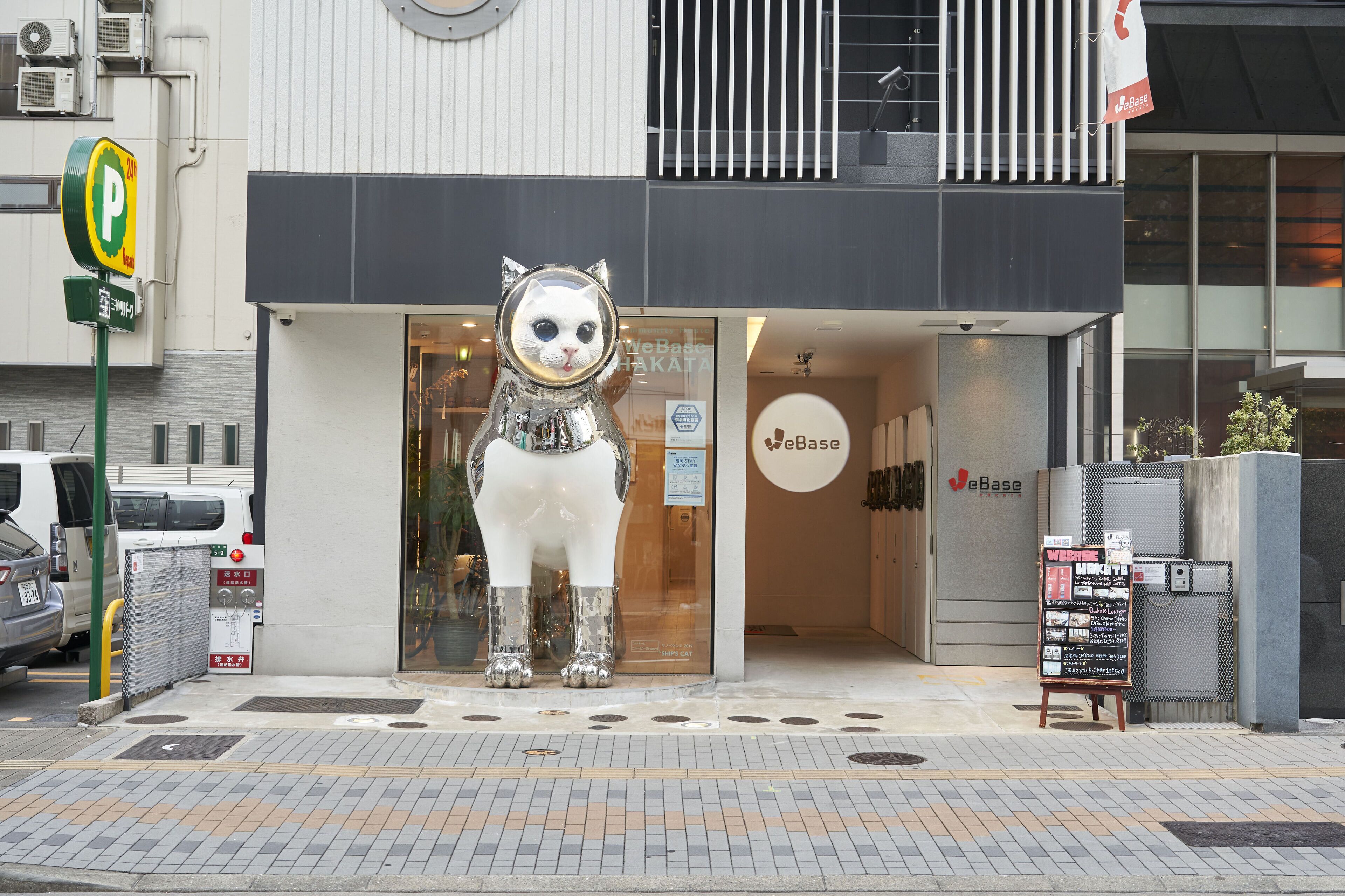 A building with a large cat statue in front, a parking sign, and a storefront with a sign that reads "eBase".