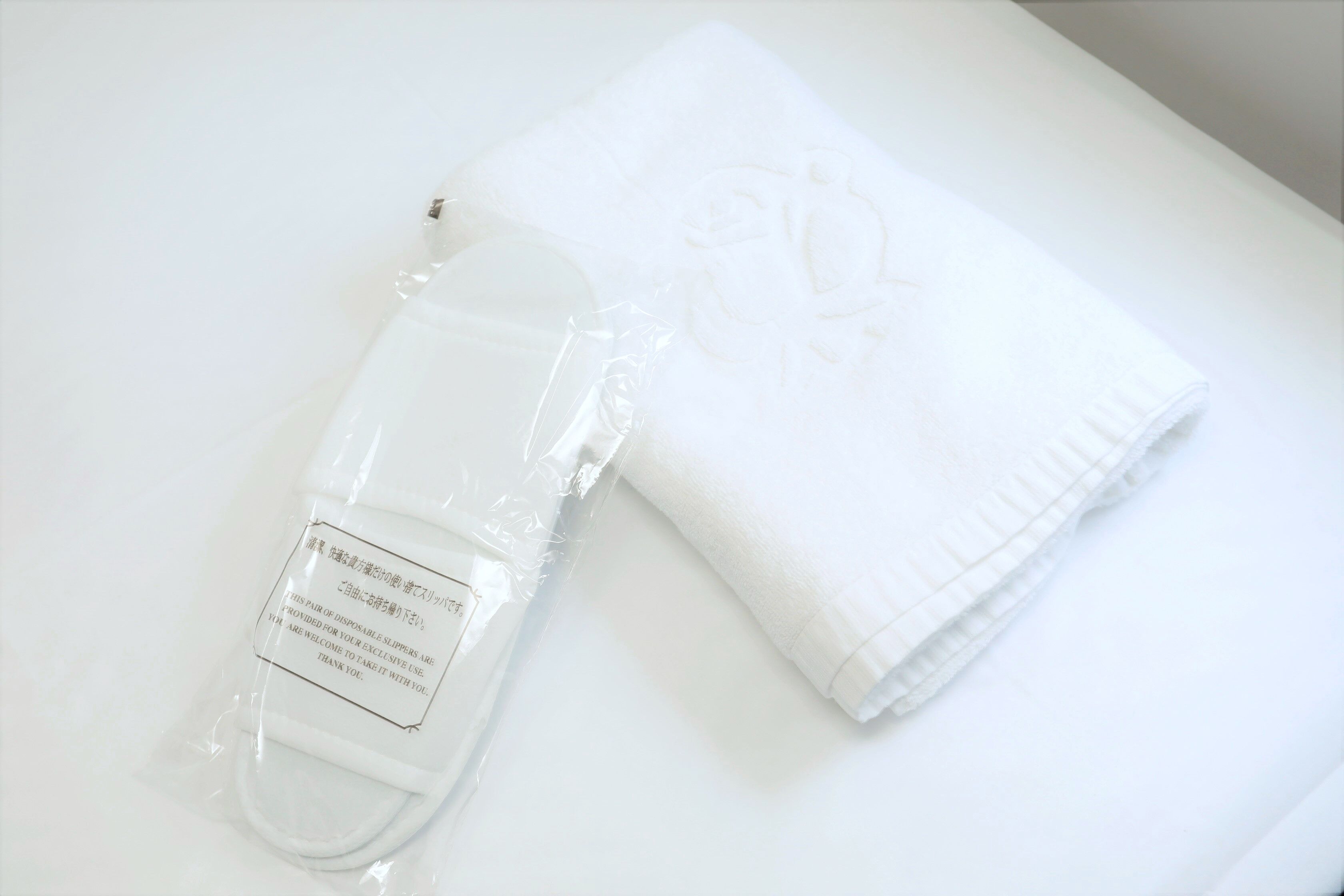 A white towel and a white bottle with a label on a white surface.