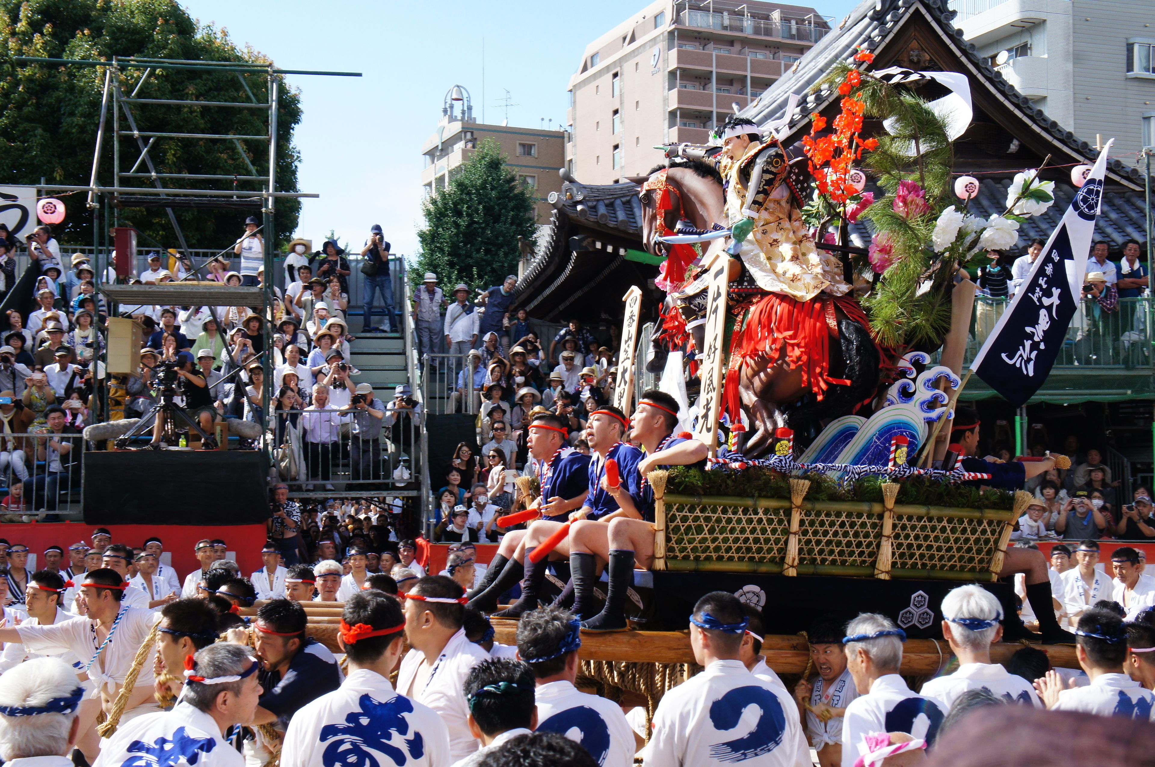 A traditional festival with a decorated float and spectators.