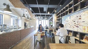 A modern cafe with brick walls, wooden tables, and hanging pendant lights.