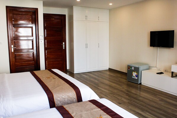 Una habitación de hotel con dos camas, un armario, un televisor y un refrigerador pequeño.