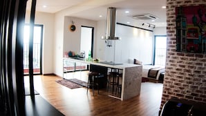 A modern kitchen with a central island, wooden flooring, and a large window. - Maxshare Hotels & Serviced Apartments (Bai Chay)