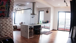 A modern kitchen with a central island, bar stools, and a large window. - Maxshare Hotels & Serviced Apartments (Bai Chay)