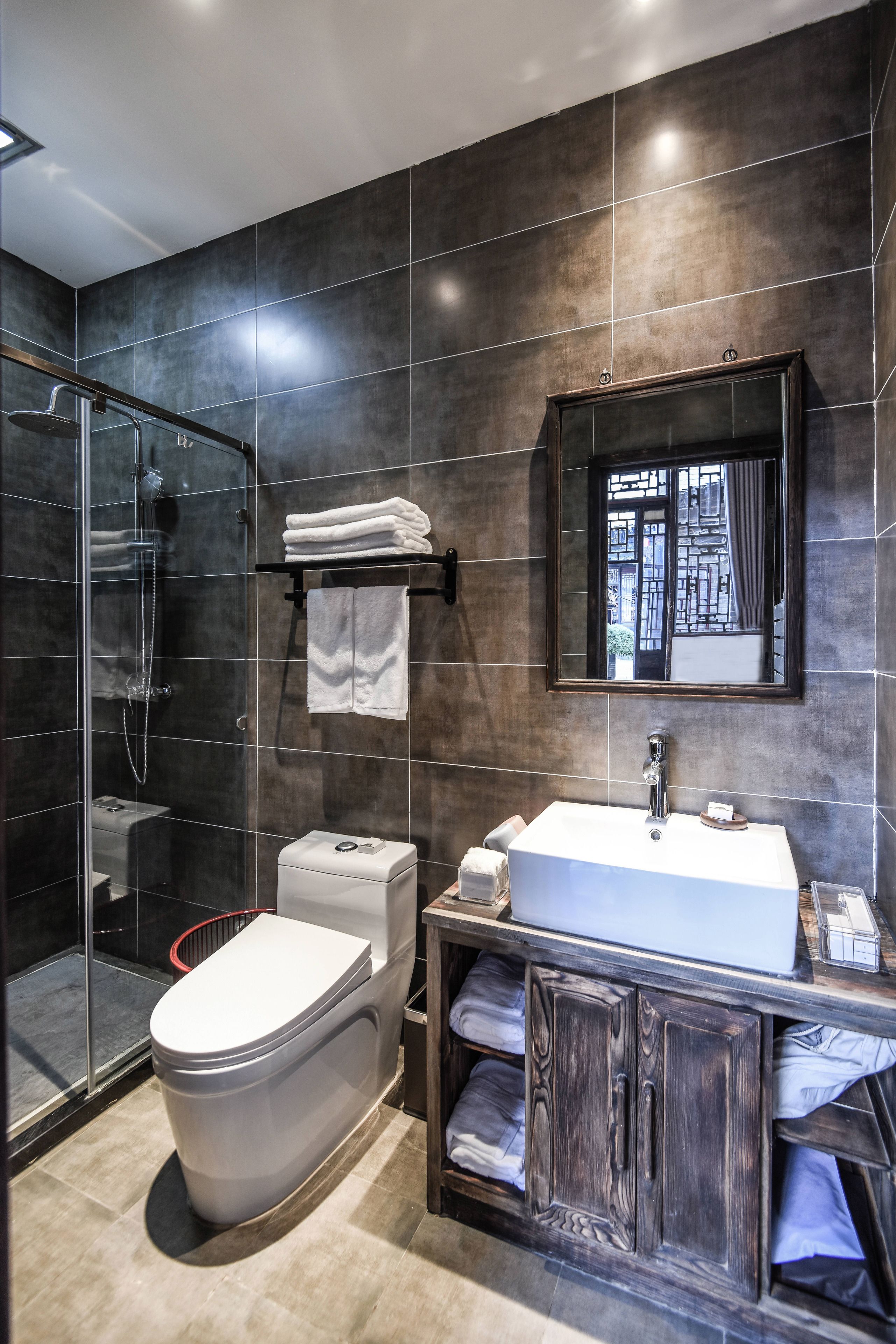 A modern bathroom with a glass-enclosed shower, a white toilet, and a vanity with a mirror.