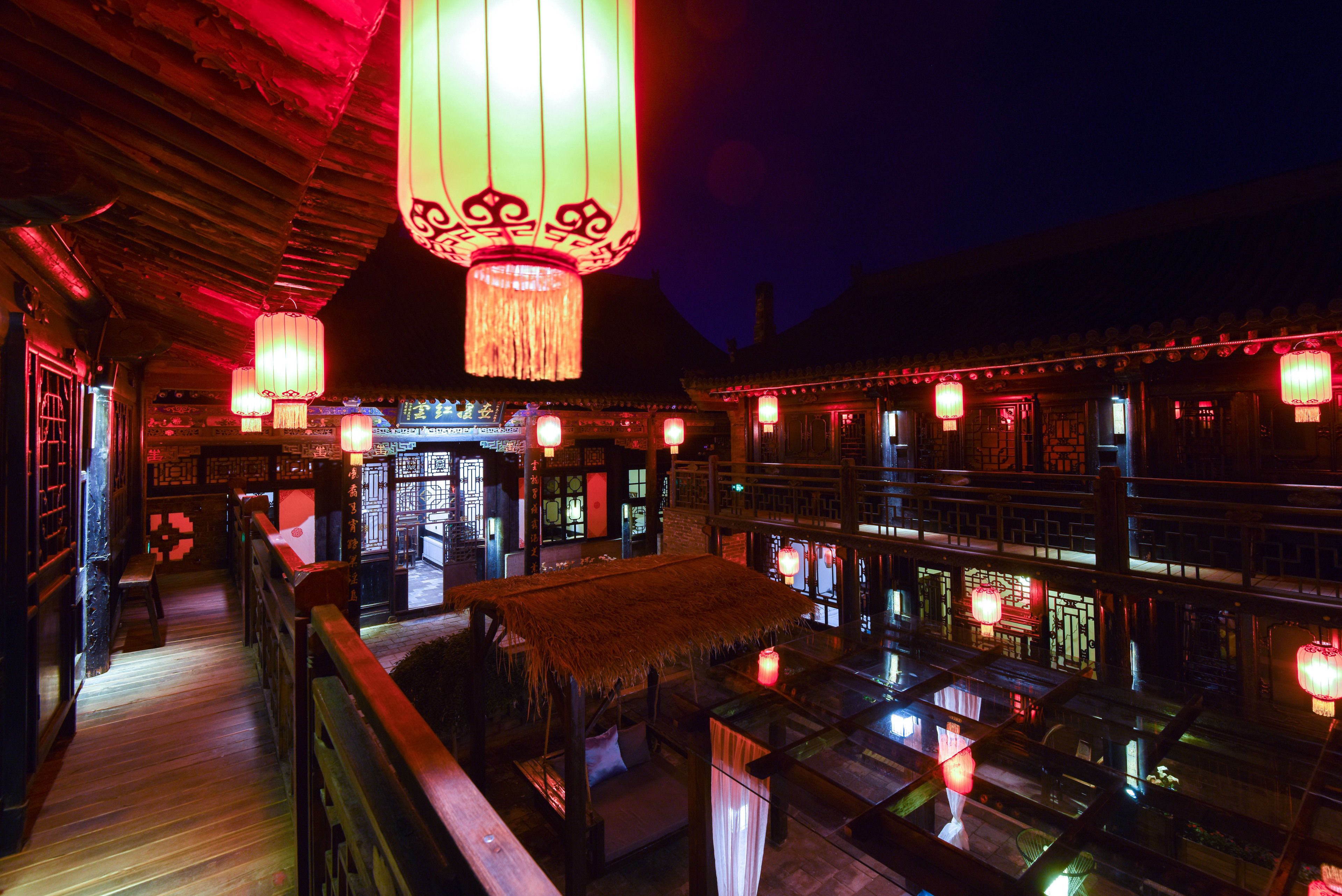 A traditional Chinese building with wooden architecture, lanterns, and a thatched roof structure.