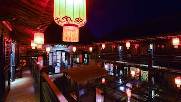 A traditional Chinese building with wooden architecture, lanterns, and a thatched roof structure.