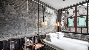 A room with a brick wall, a bed with white linens, a wooden desk with a kettle, and a window with decorative glass panes. - Elsewhere Hotel The former residence of the draft bank (Jinzhong)