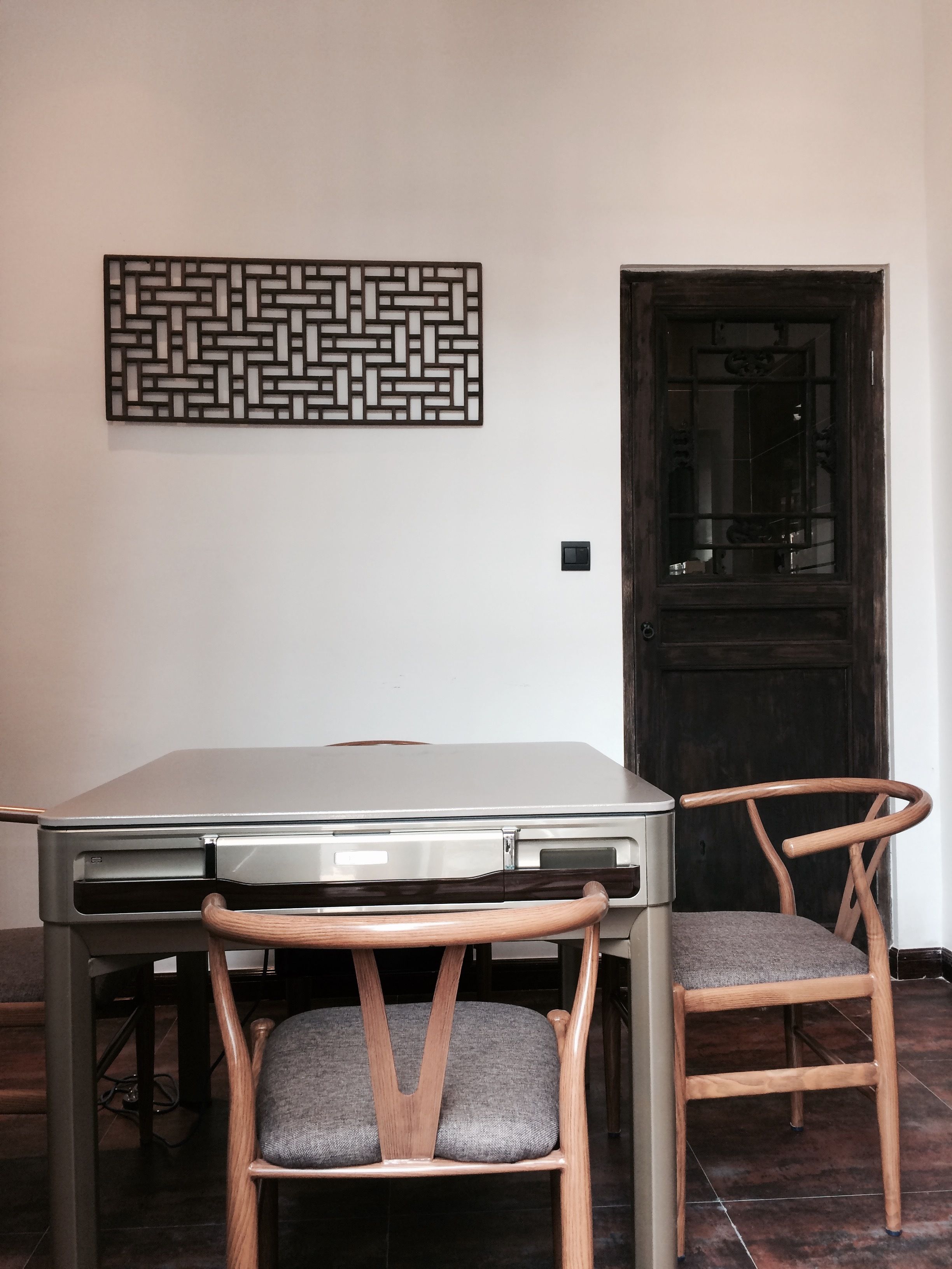 Un coin repas comprenant une table et deux chaises, un élément décoratif mural et une porte.