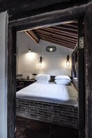 Una habitación con una cama, dos luces empotradas, una lámpara colgante y una pared de ladrillo.