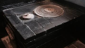 A small, dark wooden chest with a circular metal object on top, placed on a brick floor next to a black wall.