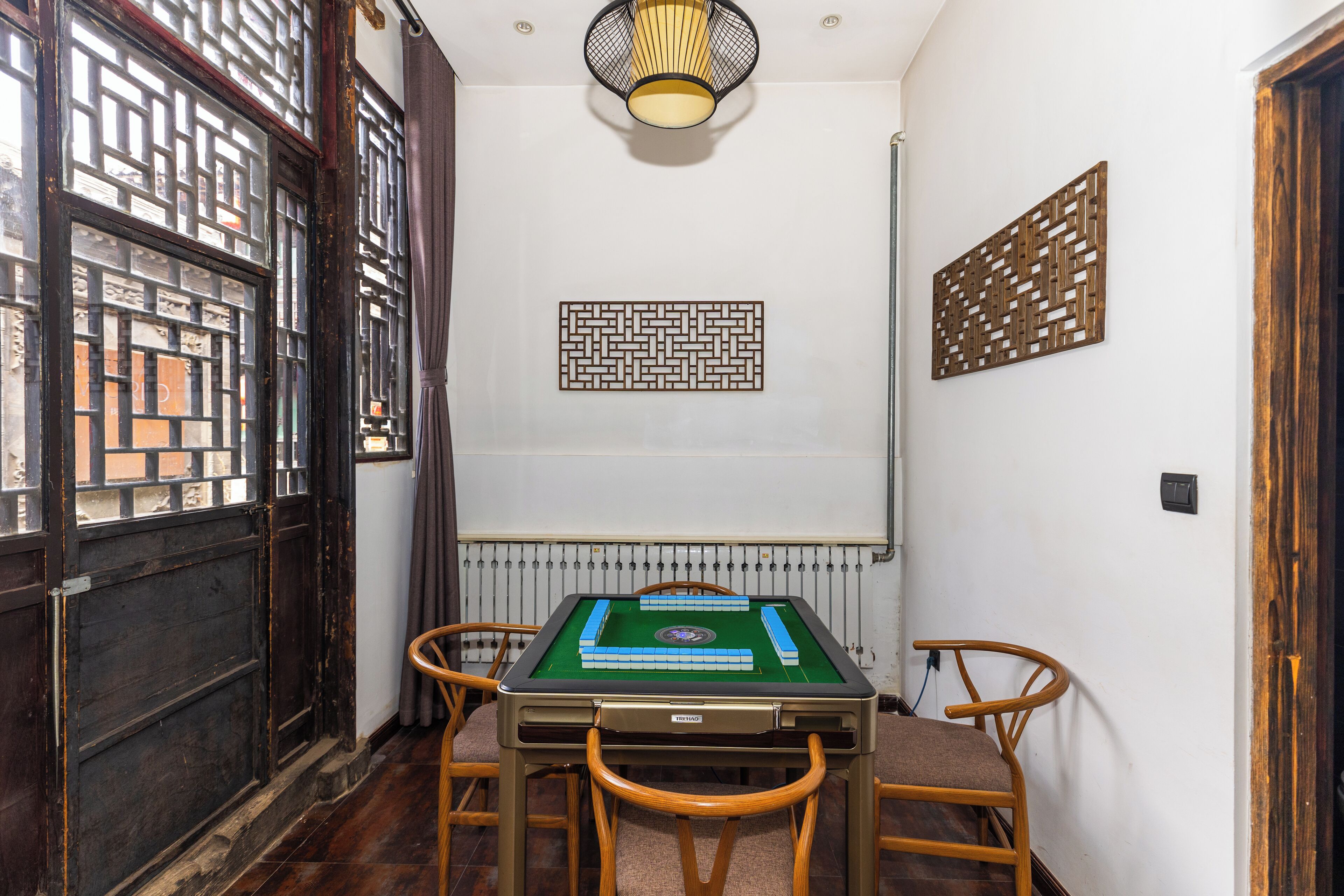 Een kamer met een pooltafel, houten stoelen, een radiator en decoratieve wandpanelen.