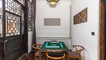 Een kamer met een pooltafel, houten stoelen, een radiator en decoratieve wandpanelen.