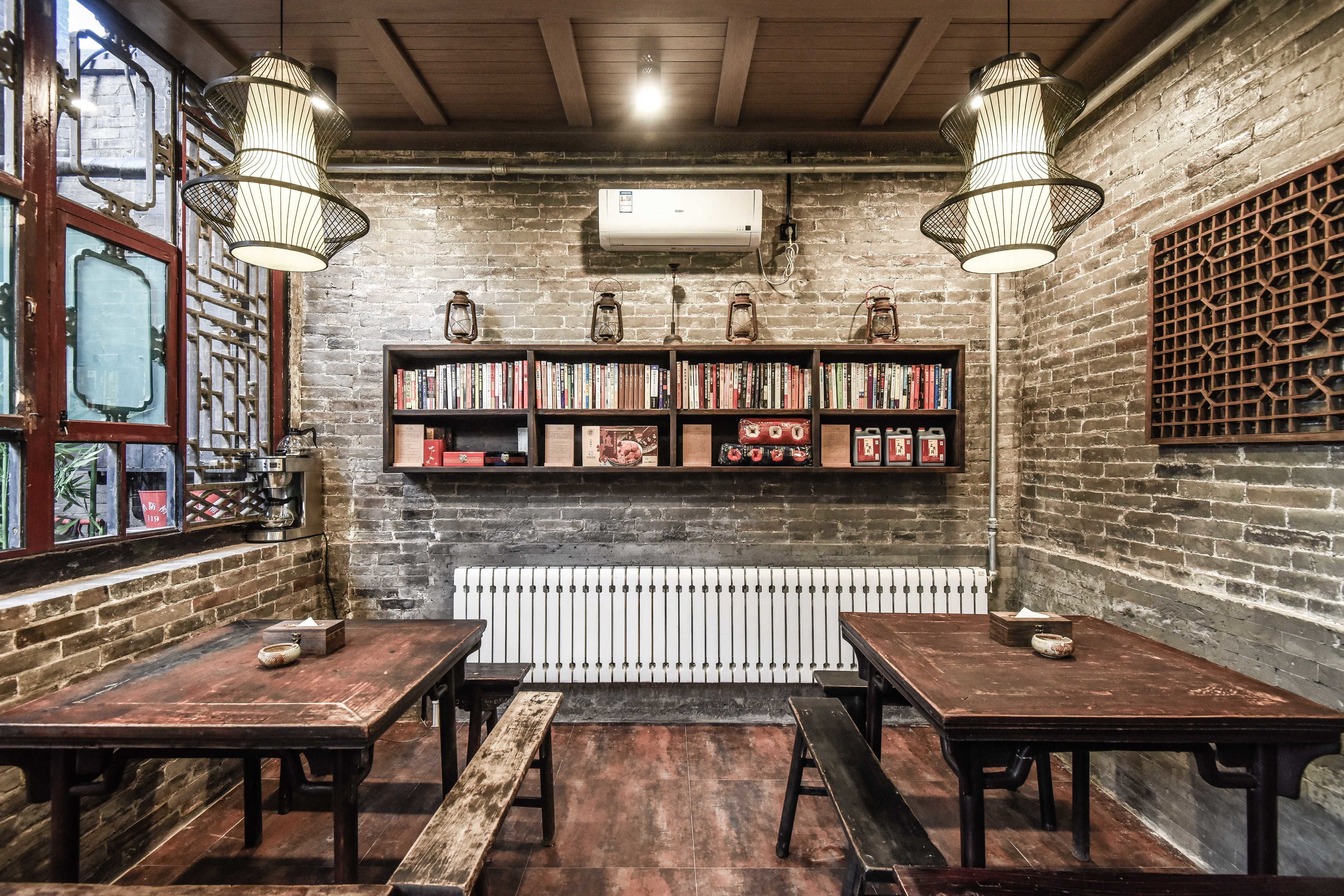 Une pièce chaleureuse avec des murs en briques apparentes, des tables en bois et des étagères remplies de livres.