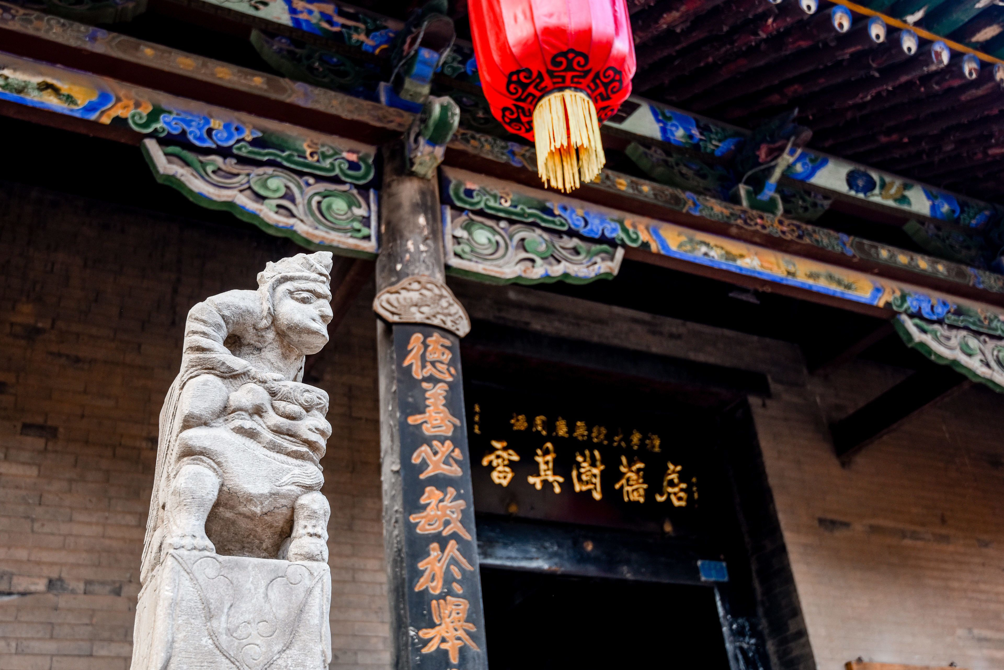 A traditional Chinese building with ornate roof decorations and a stone lion statue at the entrance.