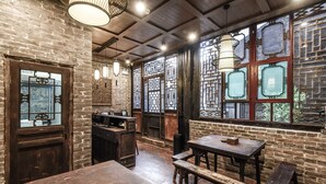 A rustic interior with exposed brick walls, wooden furniture, and traditional Chinese window designs. - Elsewhere Hotel The former residence of the draft bank (Jinzhong)
